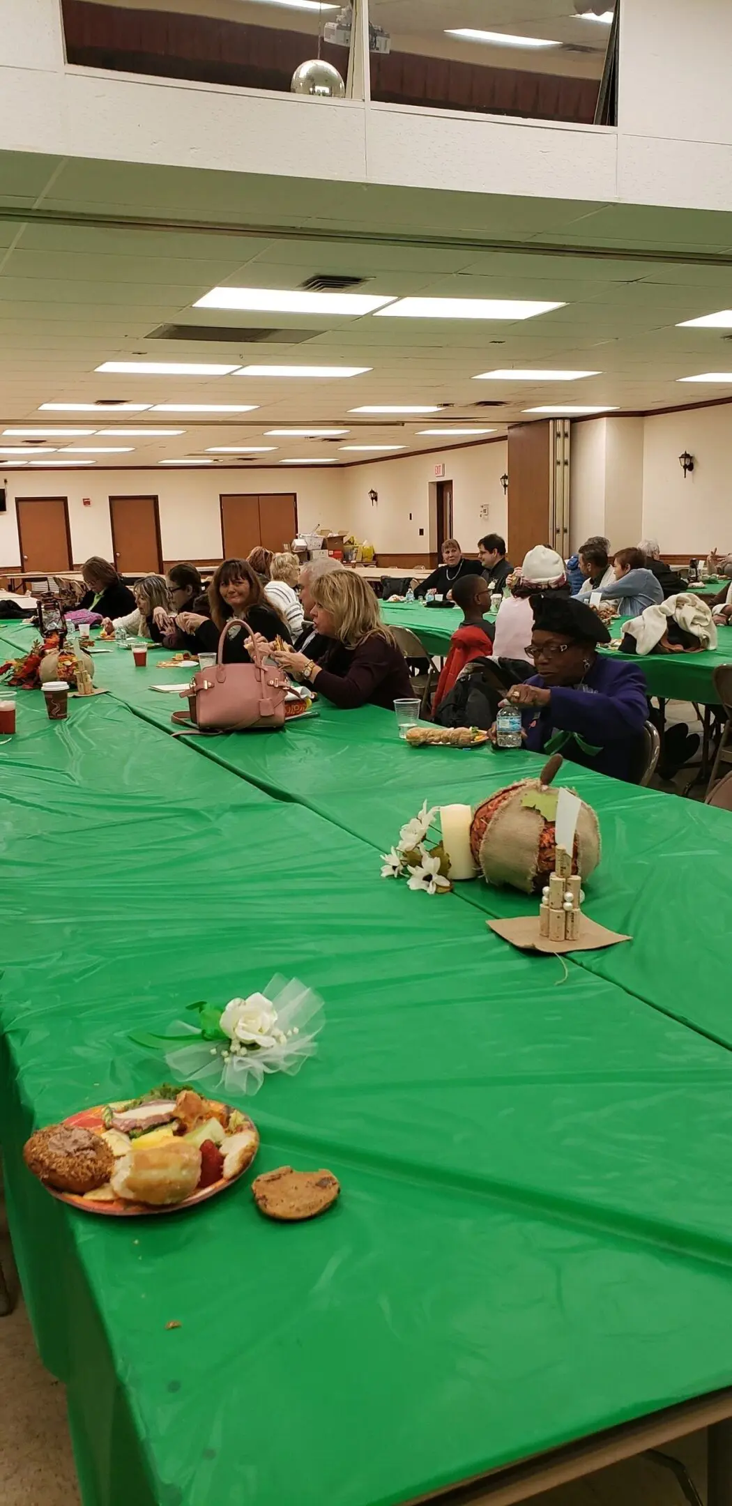 People seated at long, green-covered tables.