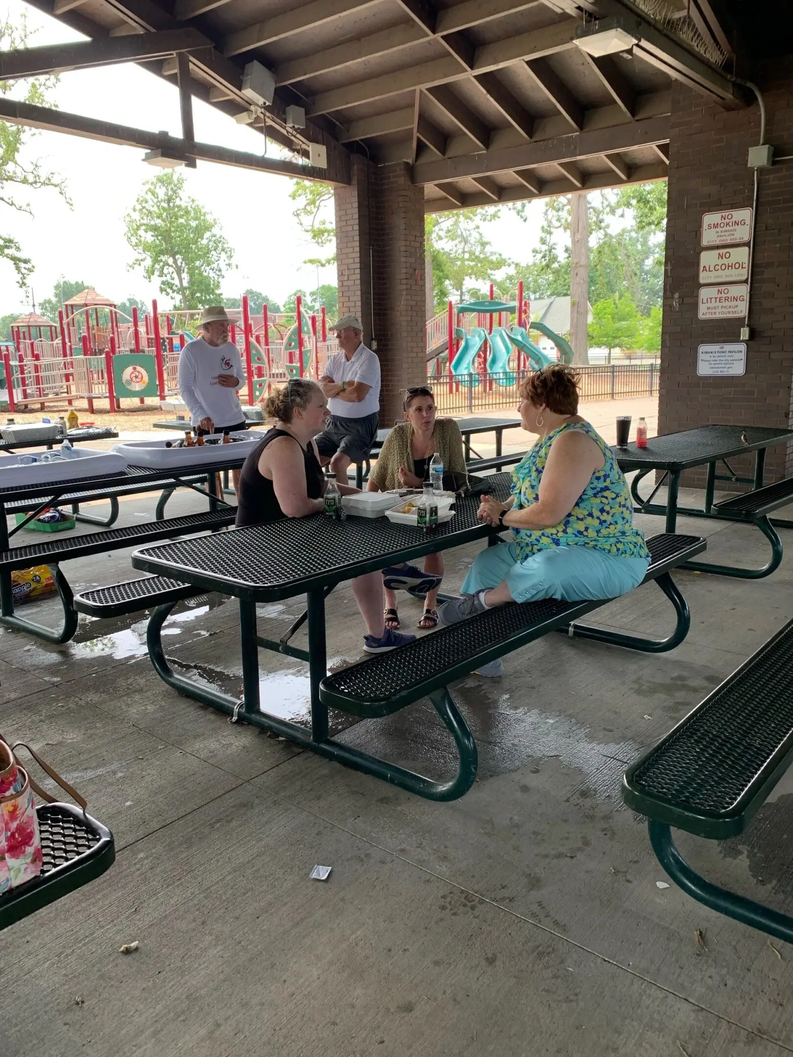 People sitting at picnic tables under shelter