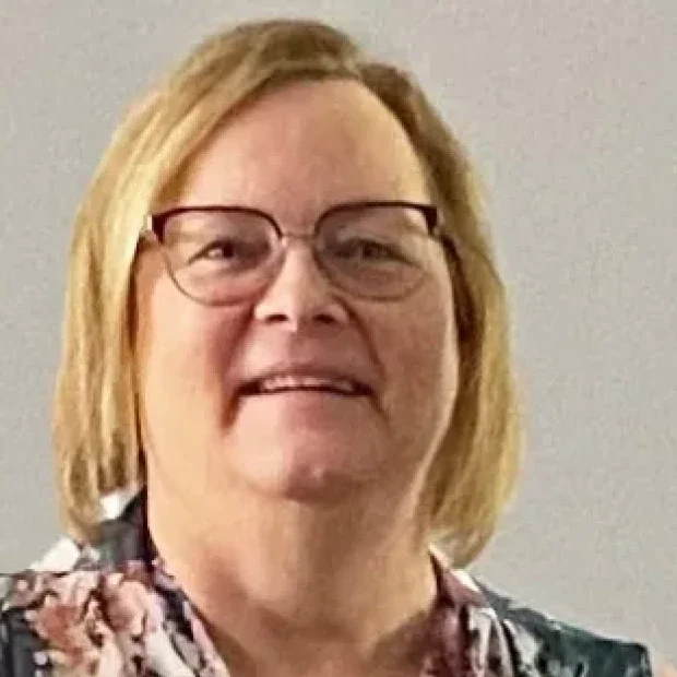 Woman in glasses against a plain background.